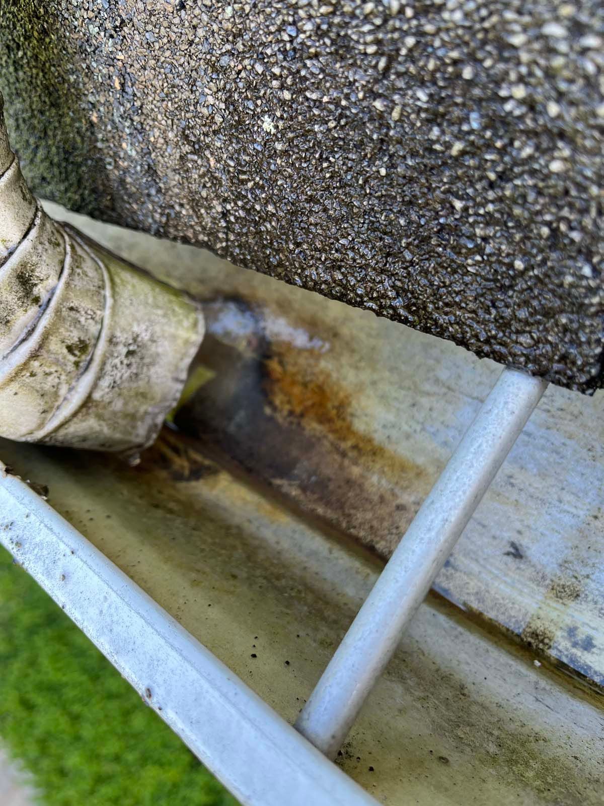 A close up of a rusty gutter on a roof.