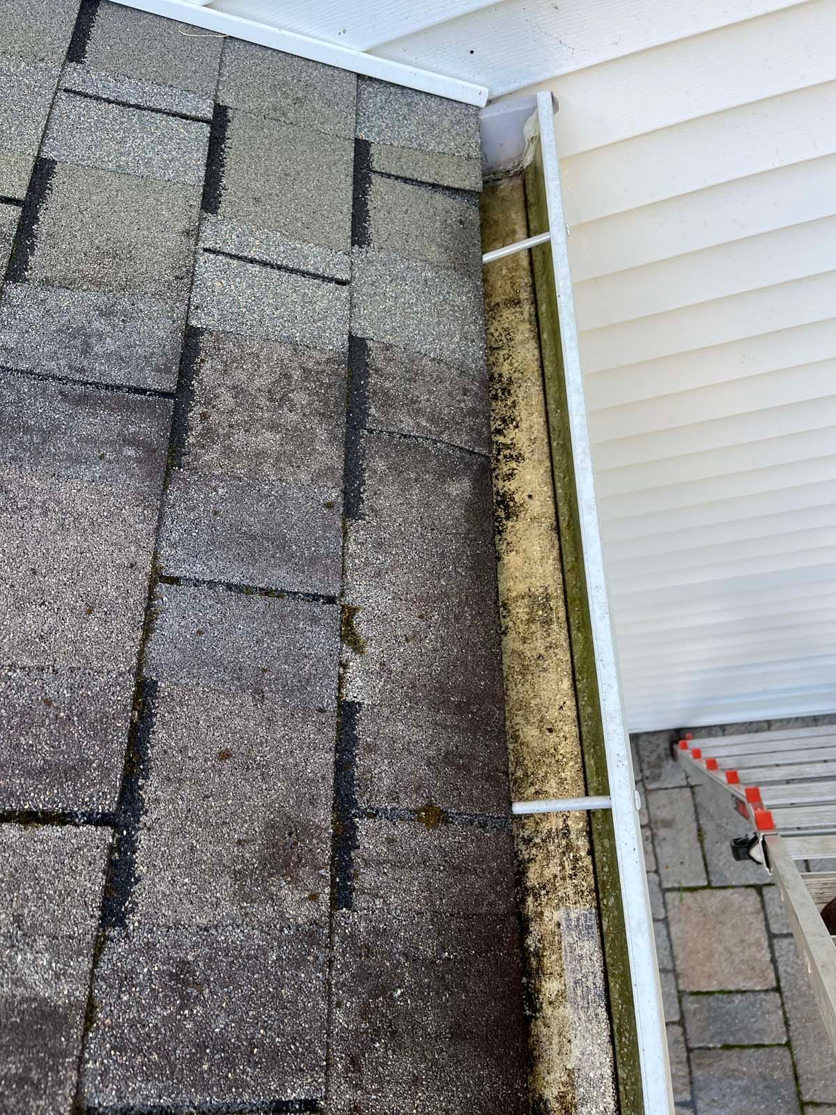 A close up of a gutter on a roof next to a house.