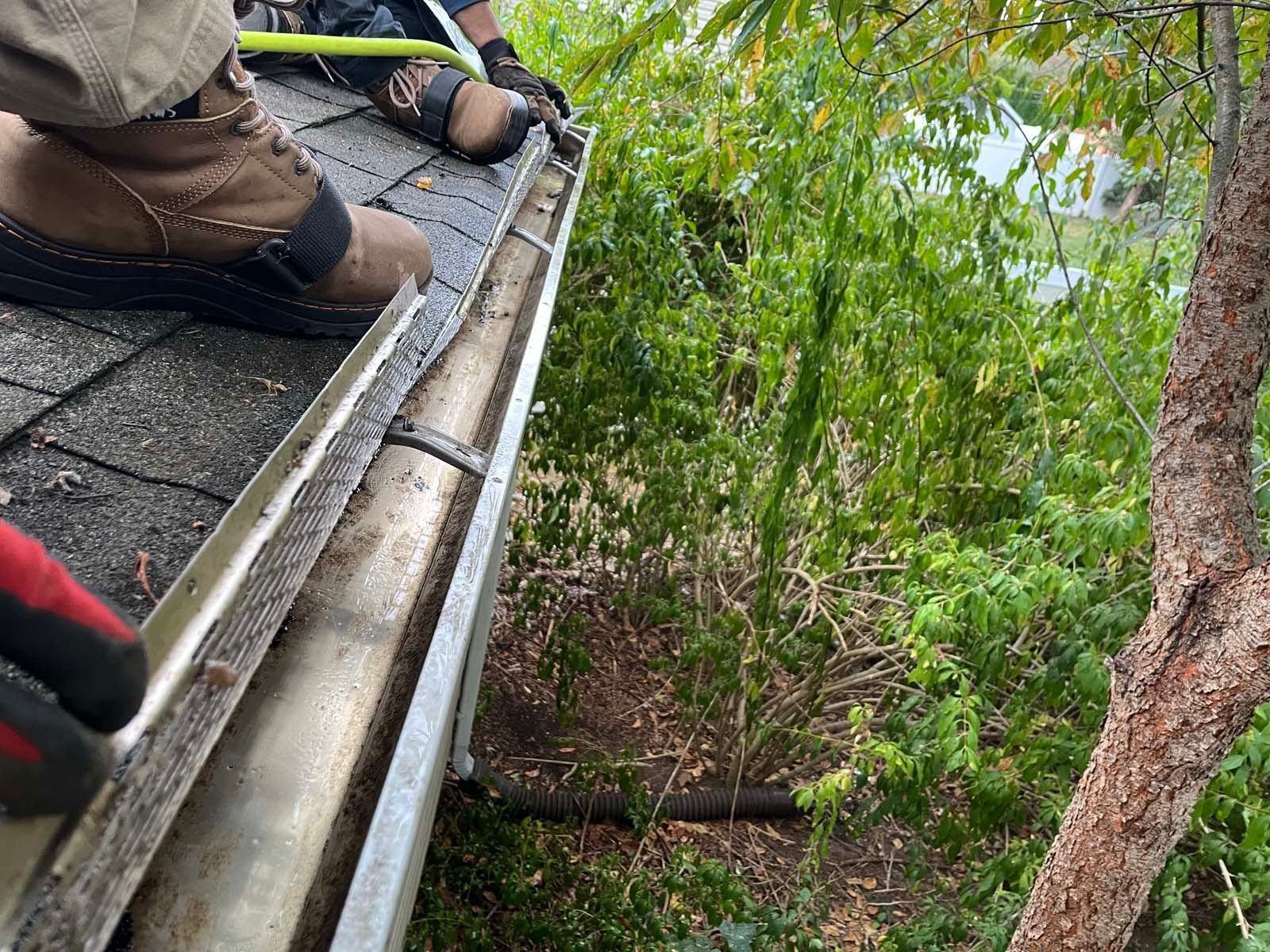 A person is working on a gutter on a roof.