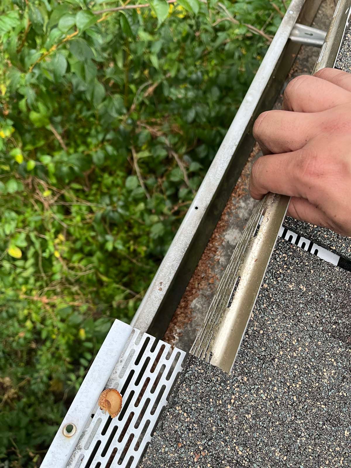 A person is fixing a gutter on a roof.