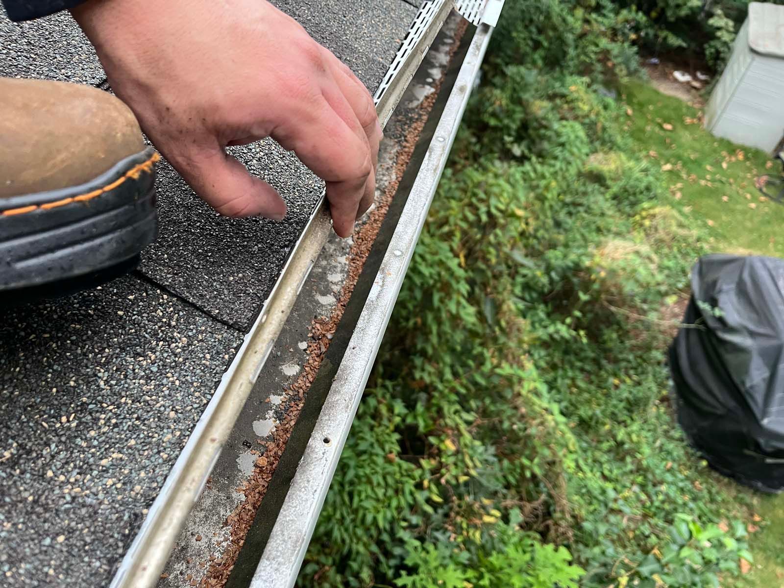 A person is cleaning a gutter on a roof.