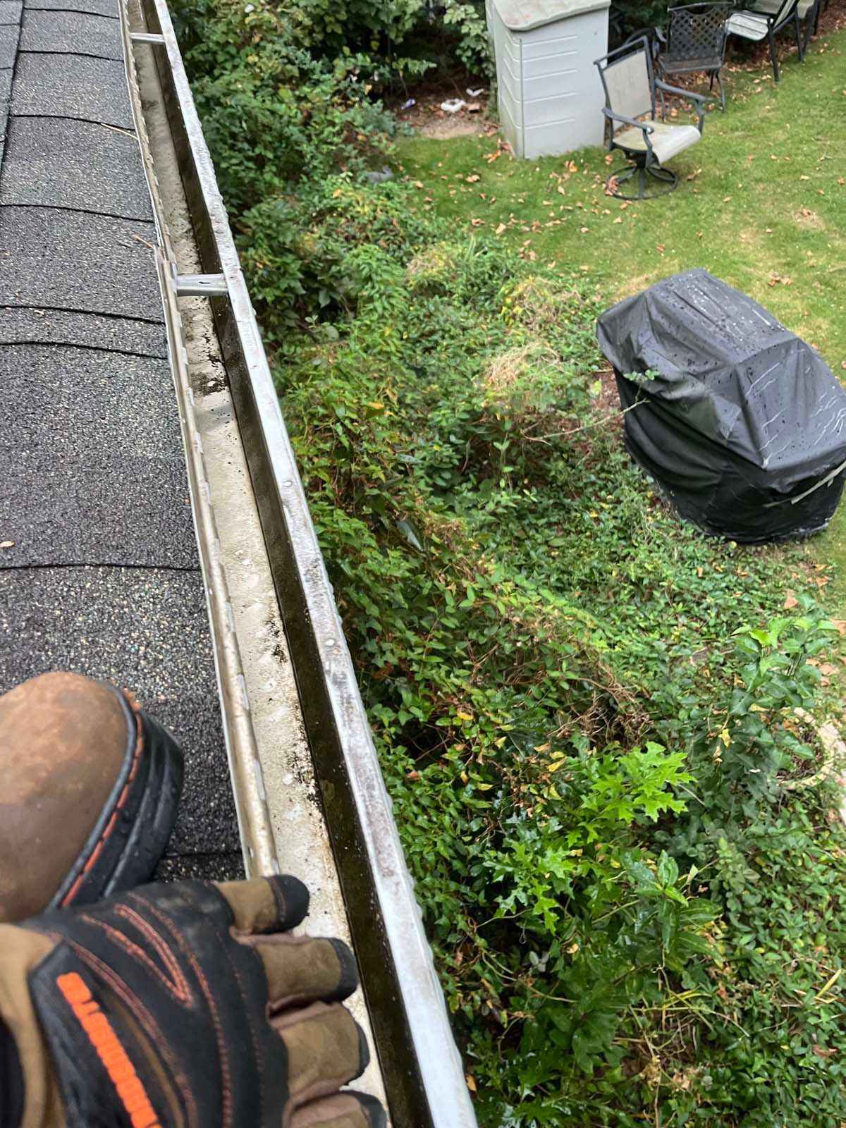 A person is cleaning a gutter on a roof.