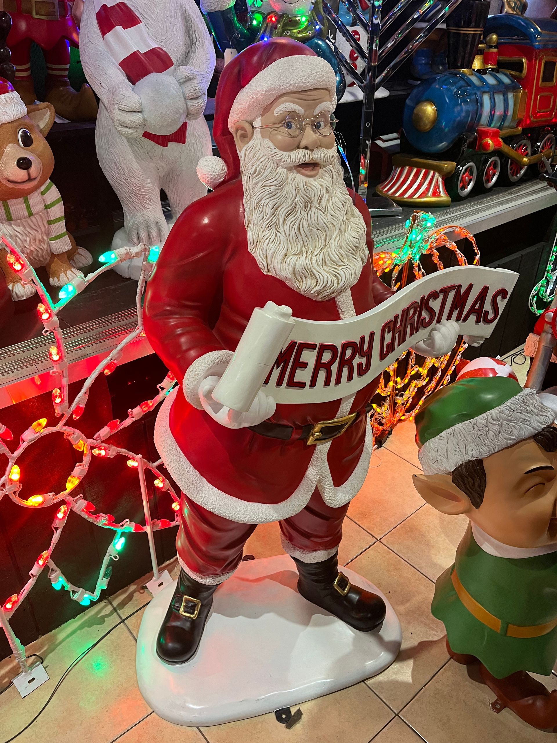A statue of santa claus holding a sign that says merry christmas
