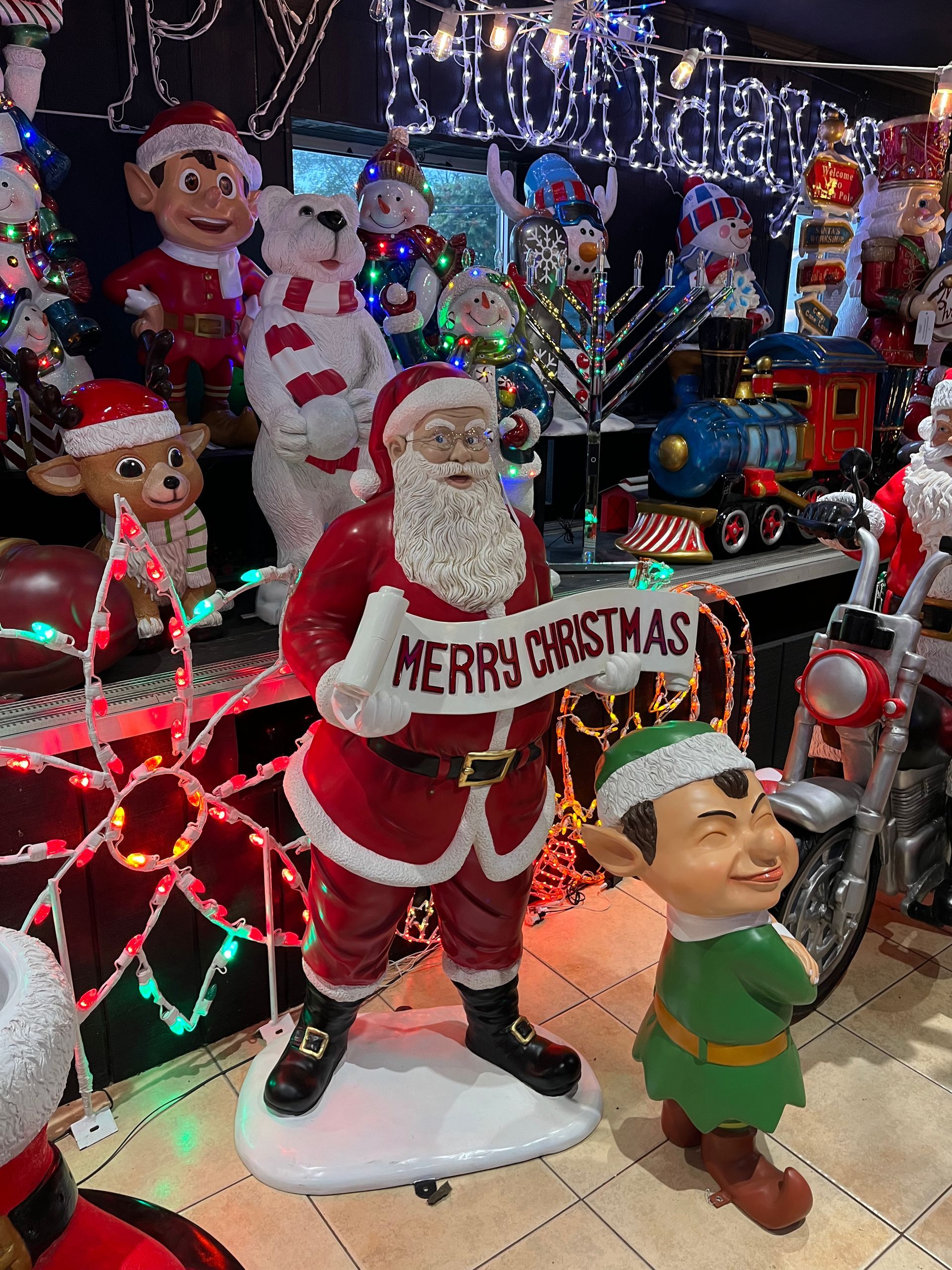 A statue of santa claus holding a sign that says merry christmas