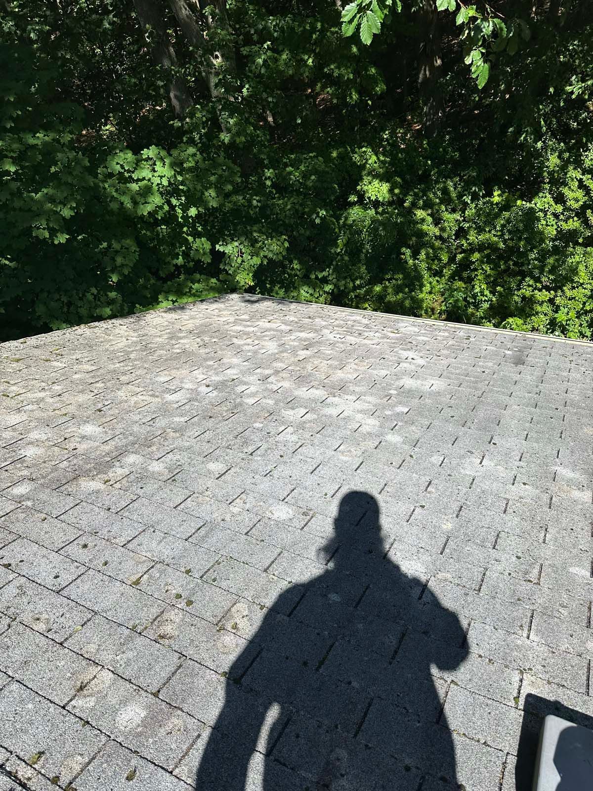 A shadow of a person is cast on a brick roof.