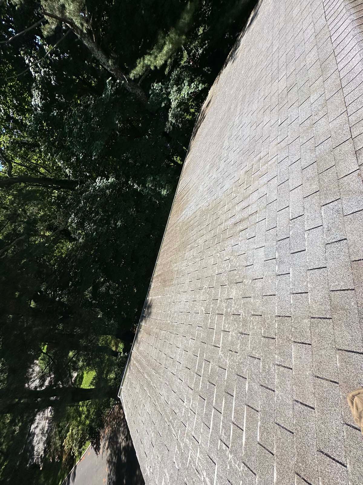 A roof with a lot of shingles and trees in the background.