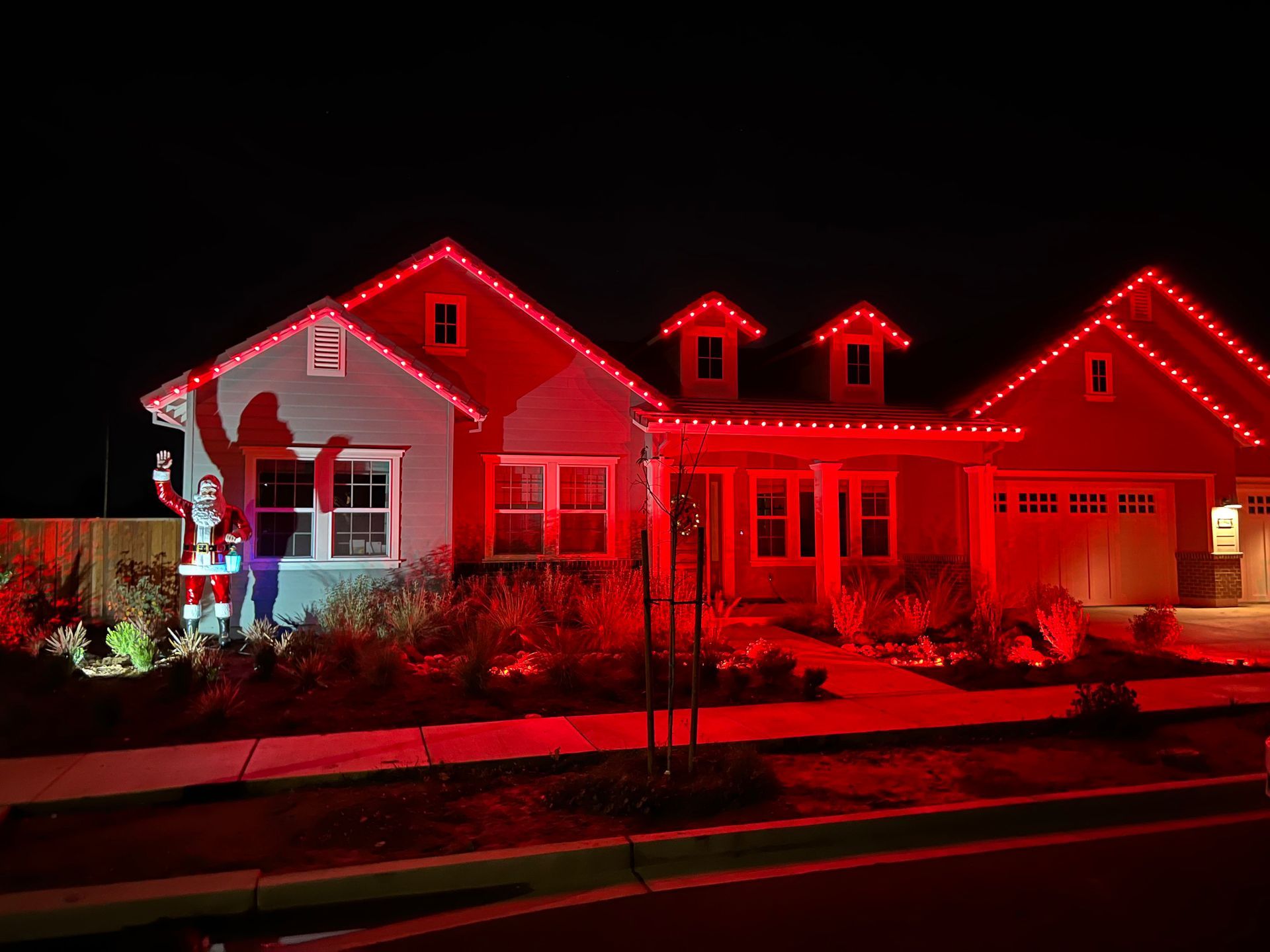 A house is decorated with red christmas lights at night.