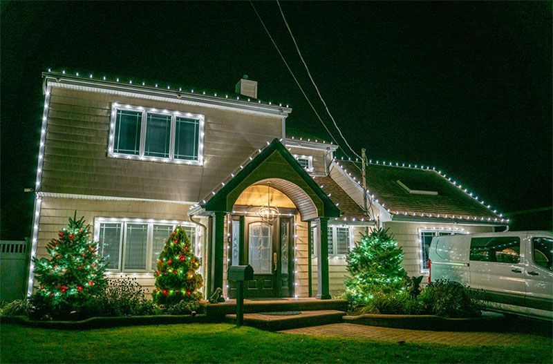 House decorated with white and green Christmas lights at night.