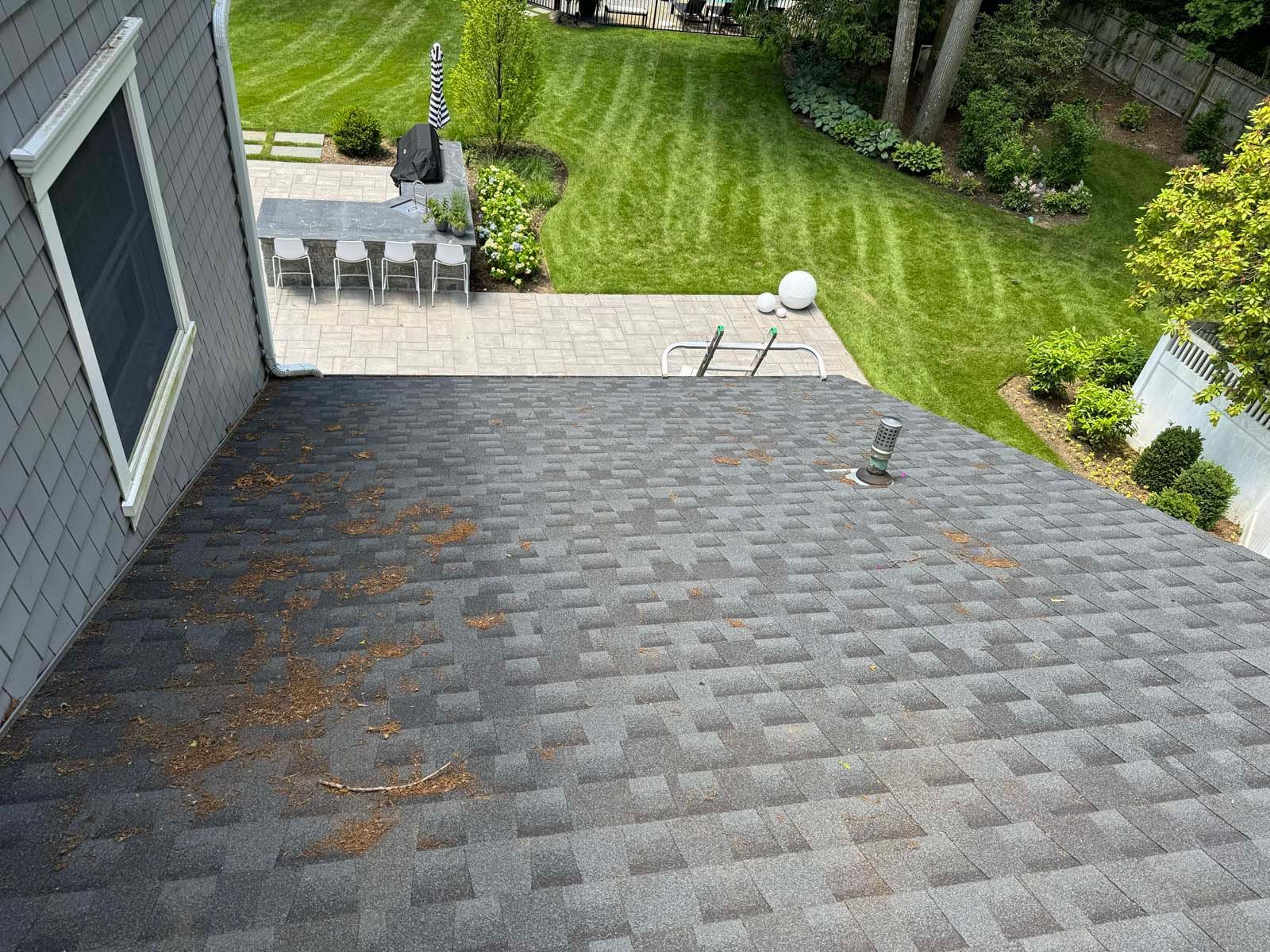 An aerial view of a roof with a patio and lawn in the background.