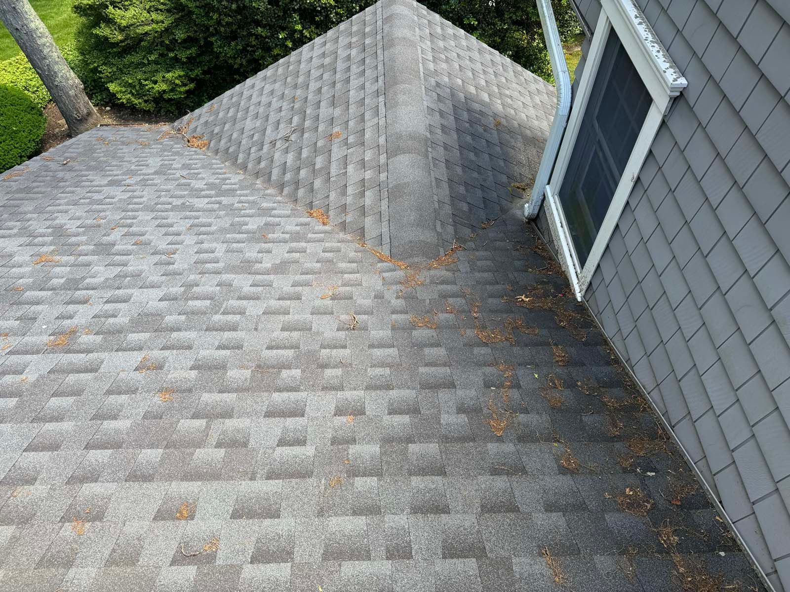 A roof of a house with a triangle shaped roof and a window.