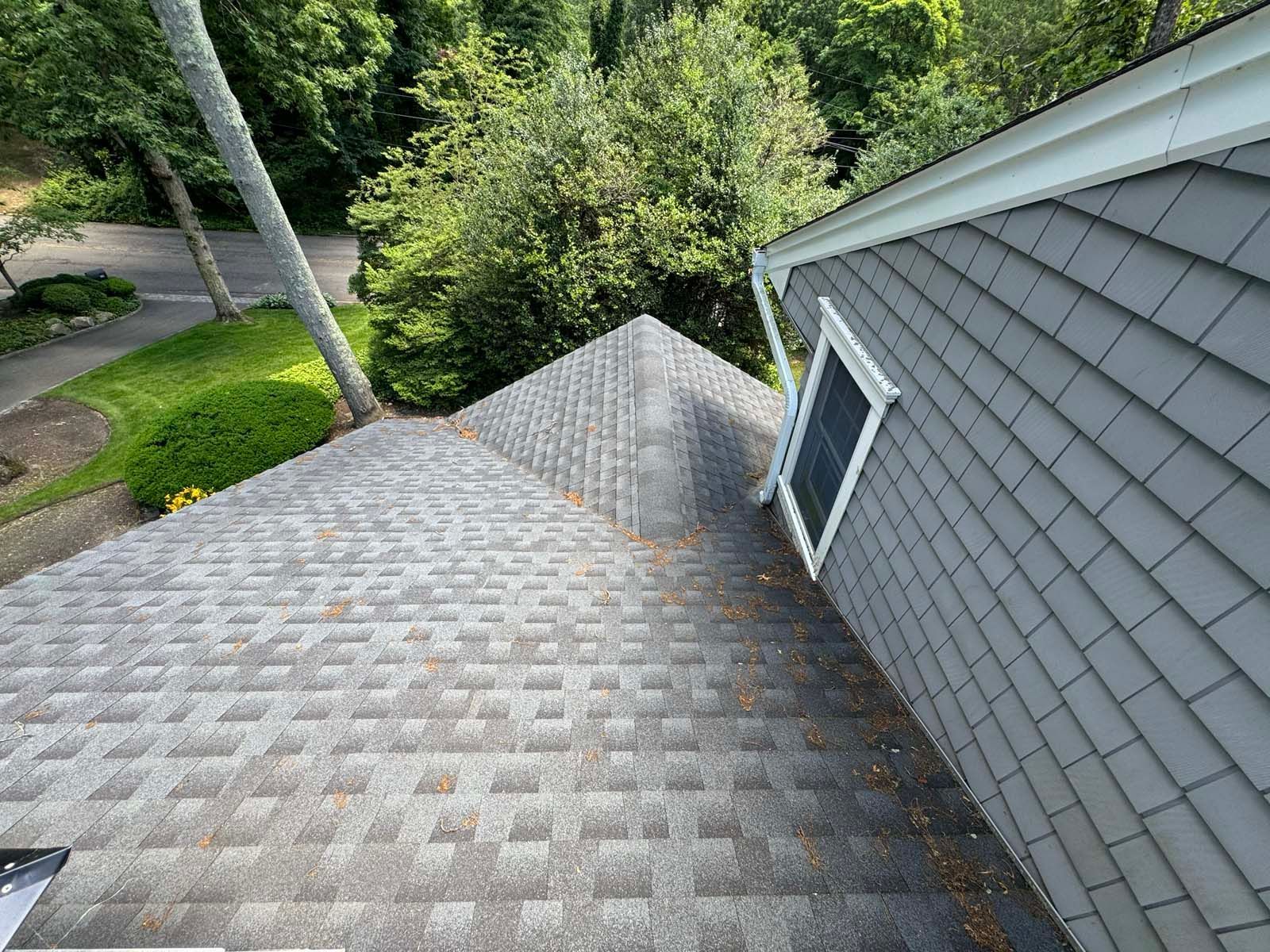 An aerial view of a roof of a house with trees in the background.