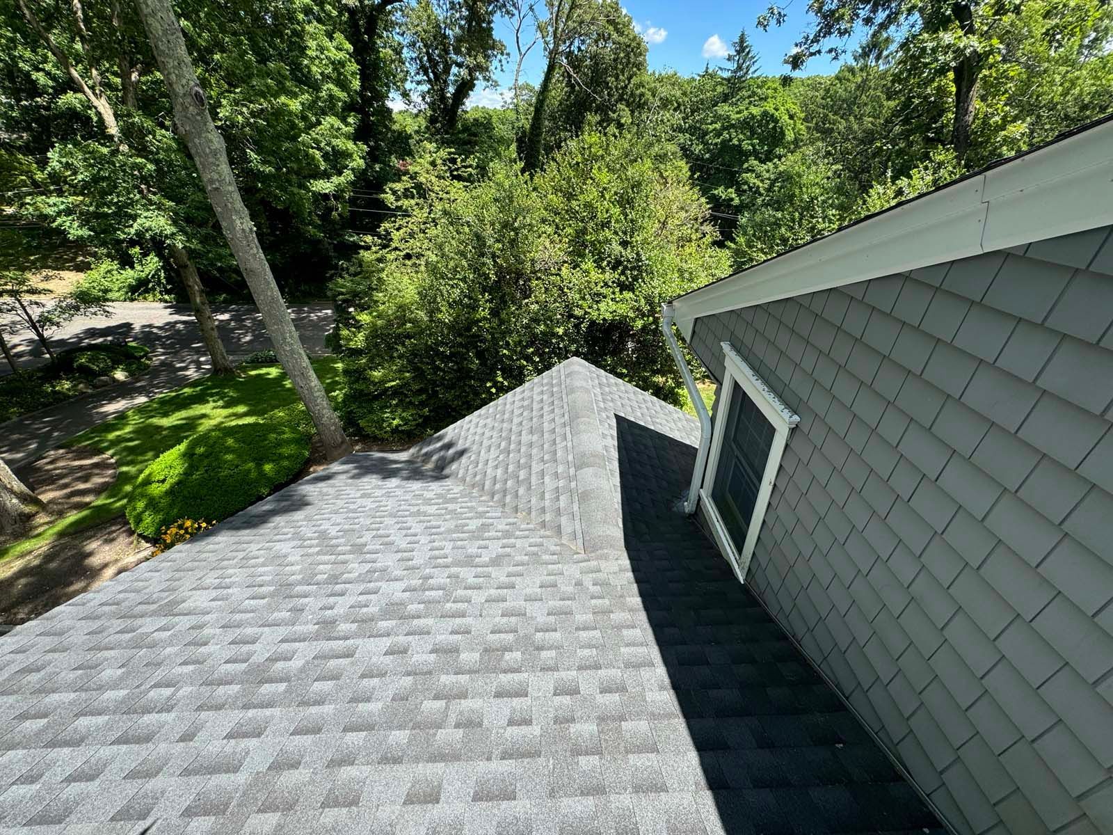 A house with a roof that is surrounded by trees.