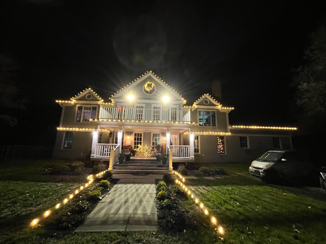 A large house is decorated with christmas lights at night.