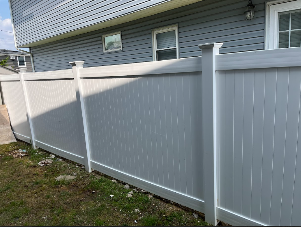 A white vinyl fence is in front of a house.