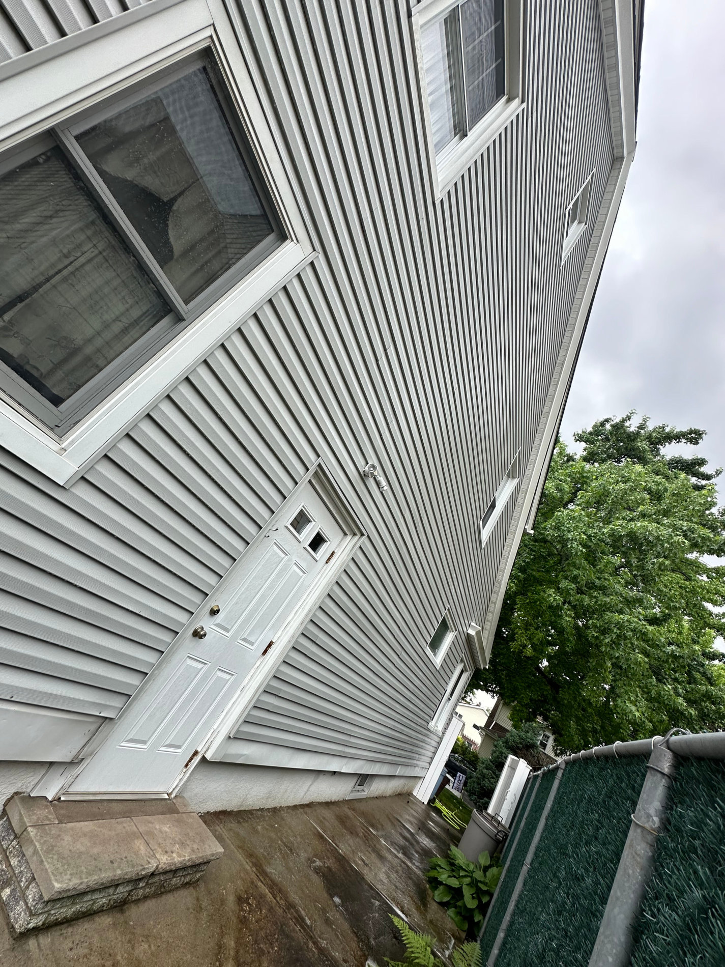 The side of a house with a white door and windows.