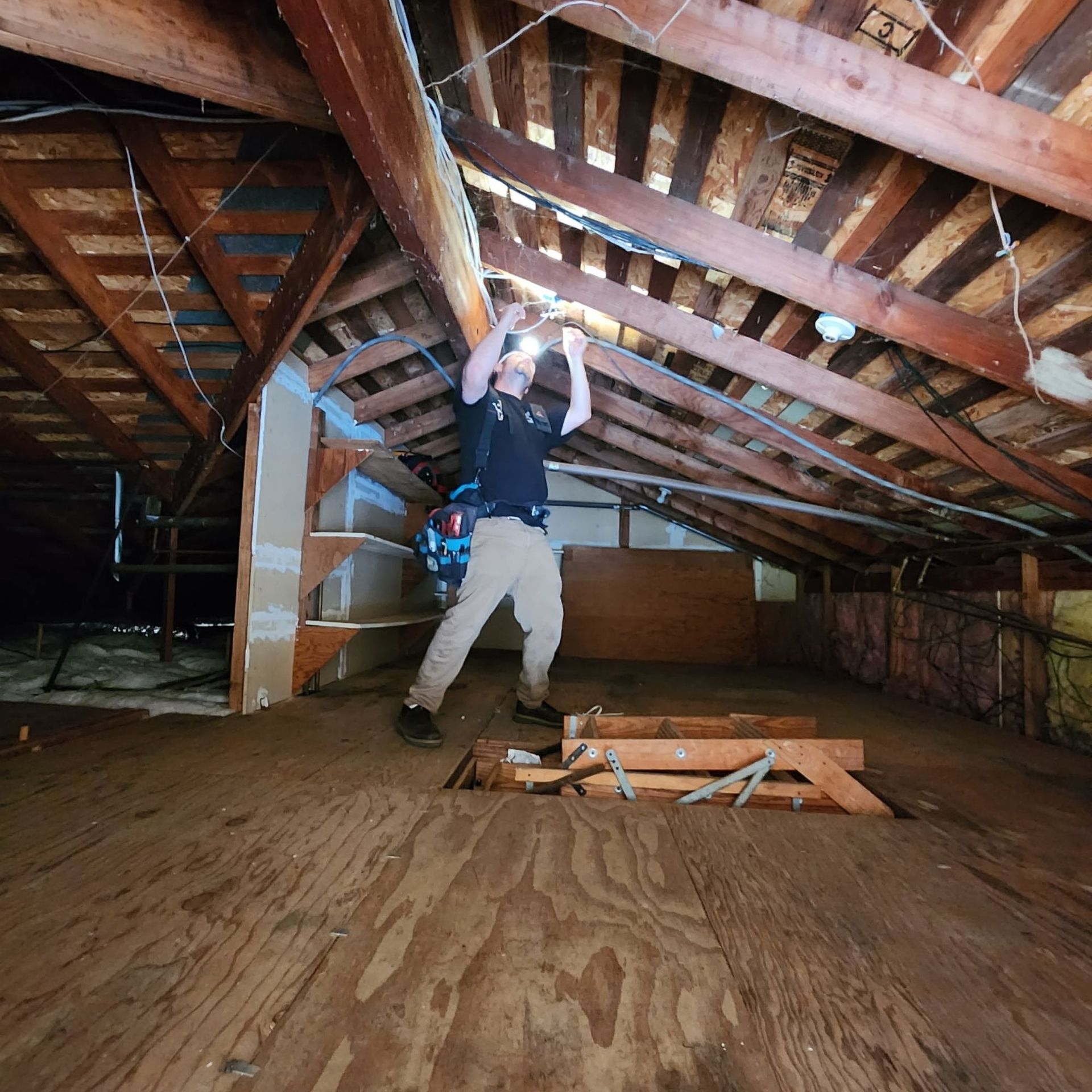The Electric Pro - A man is standing in an attic with a light on his head