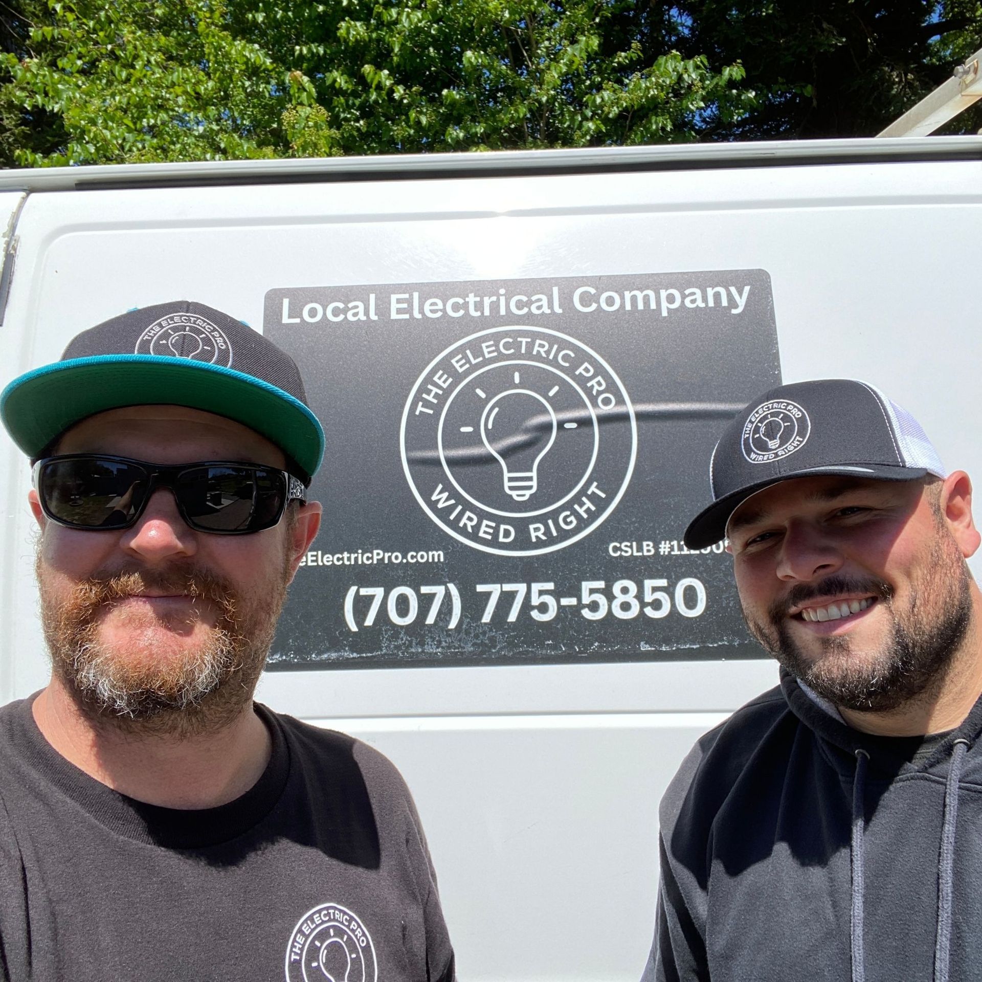 The Electric Pro - Two men are posing for a picture in front of an electrical company van.