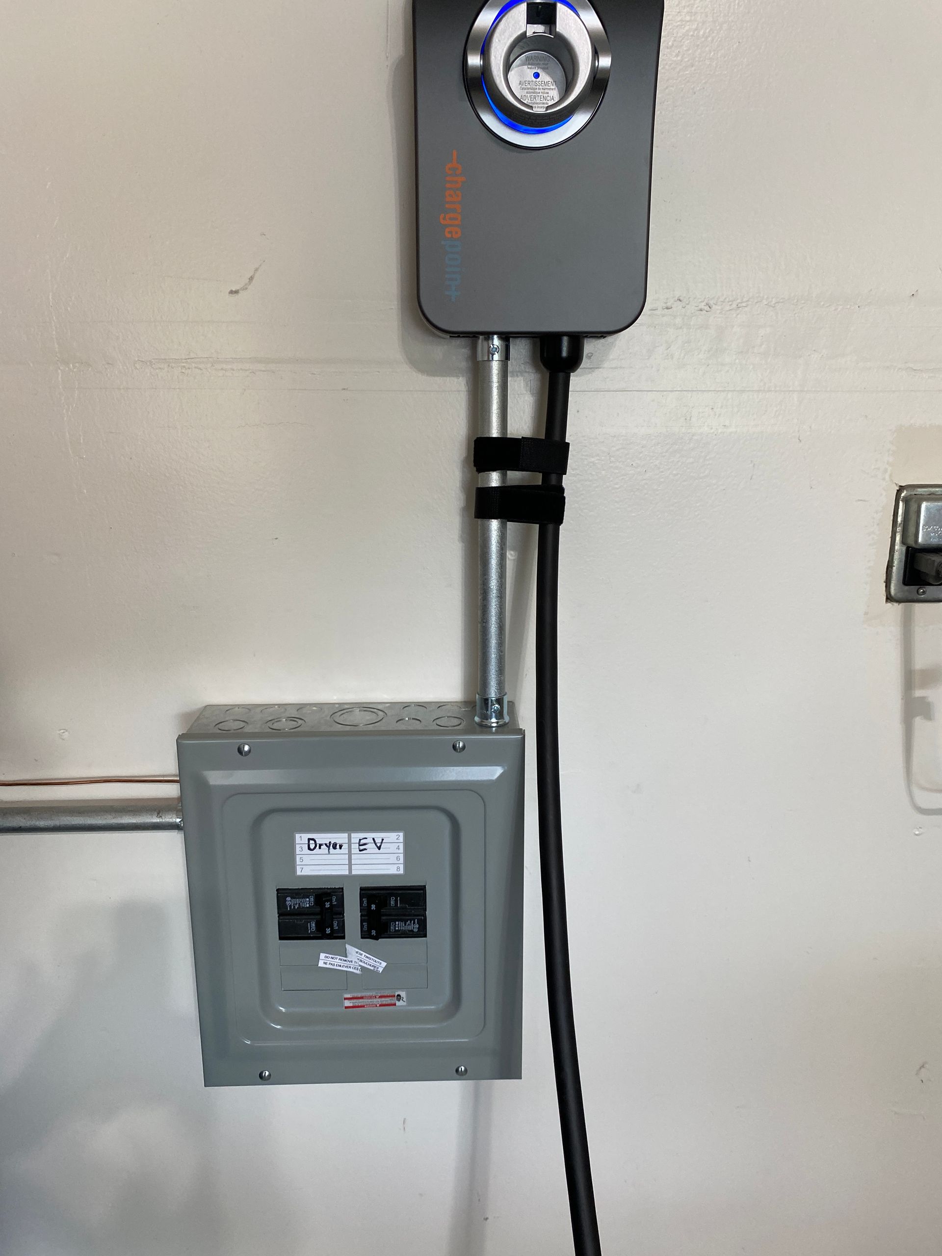 The Electric Pro - A electrical box is hanging on a wall next to a light switch.