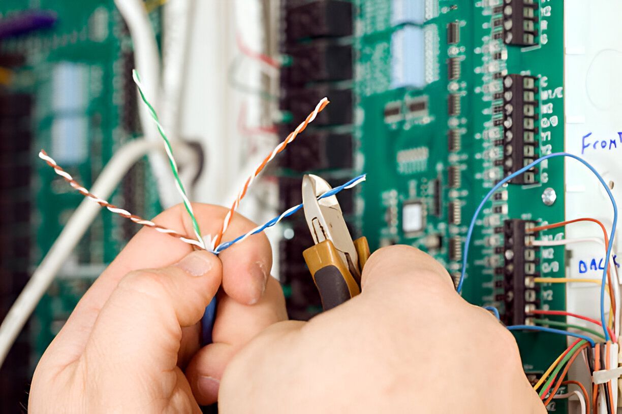 The Electric Pro - A person is working on a circuit board with a pair of pliers.