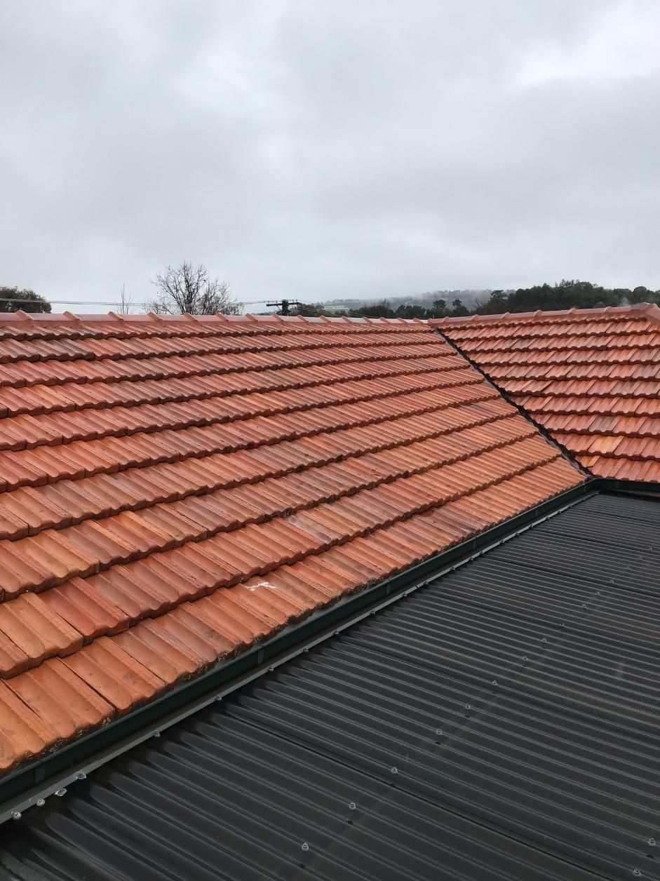 A close up of a tiled roof with a cloudy sky in the background  — Roofworx Group In Bathurst, NSW
