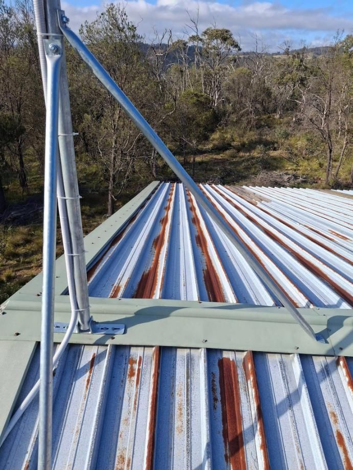 A Rusty Metal Roof With A Metal Pole Attached To It — Roofworx Group In Bathurst, NSW
