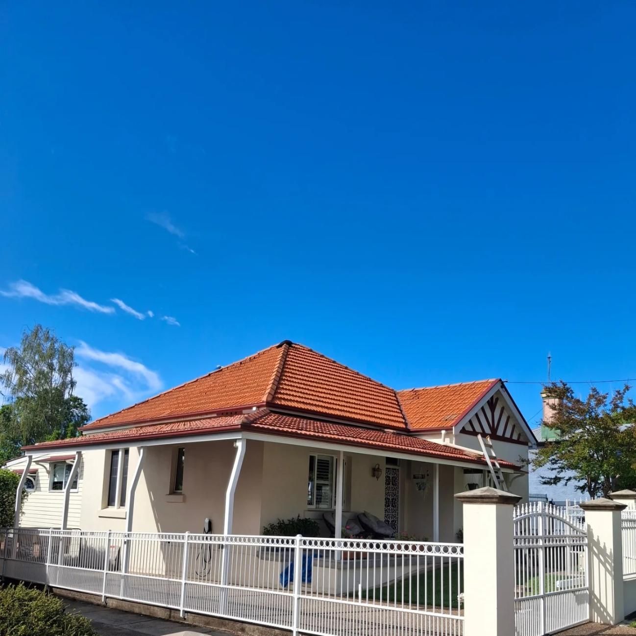 A White House With A Red Tile Roof And A White Fence — Roofworx Group In Bathurst, NSW
