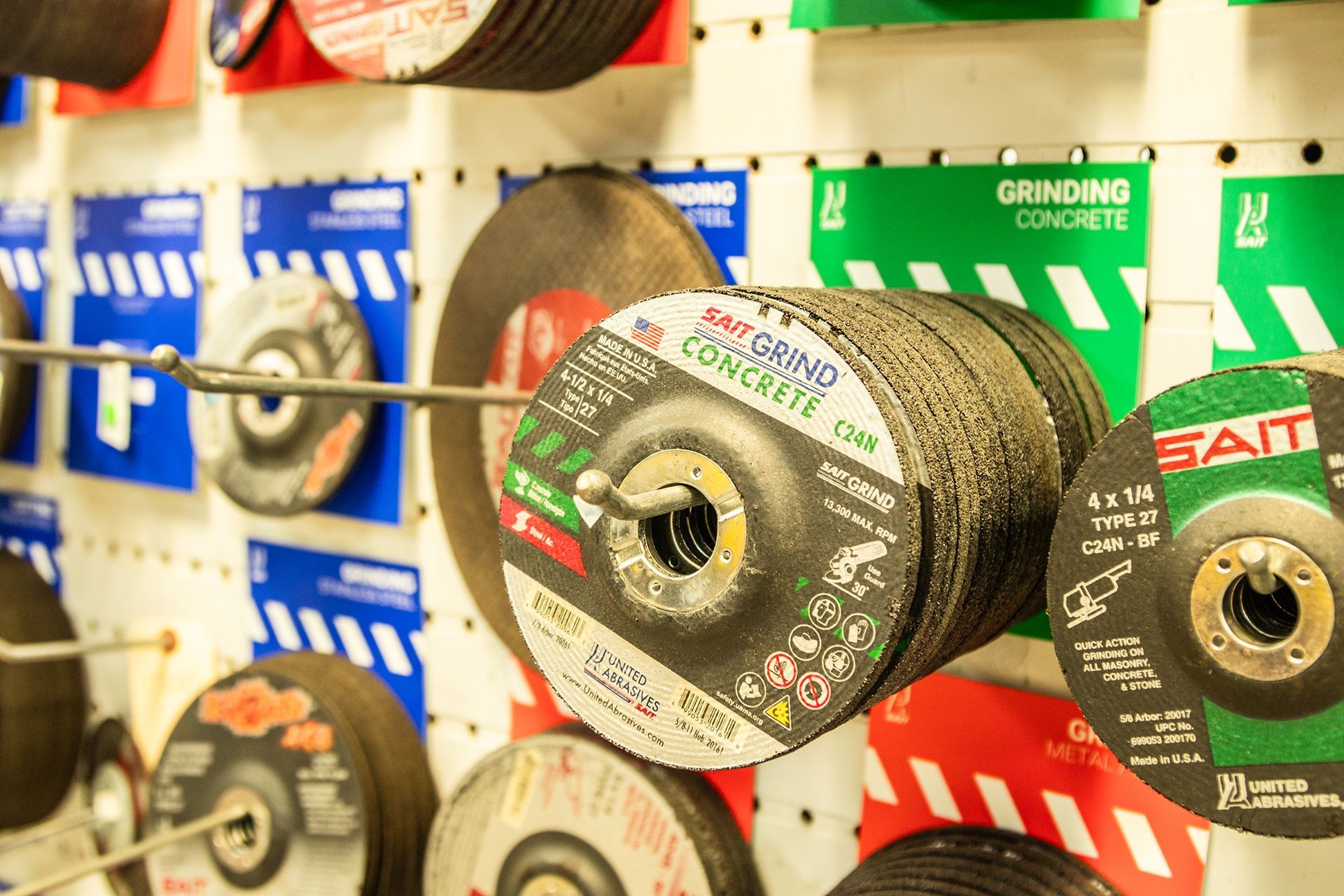 A bunch of grinding wheels are hanging on a wall in a store.