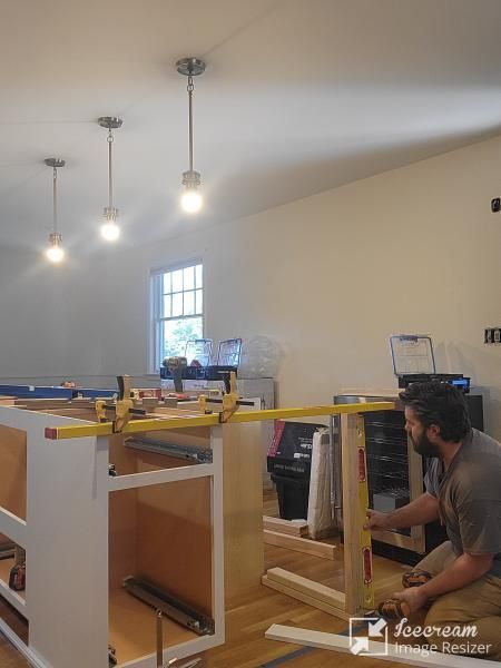 A man is measuring a piece of wood in a kitchen