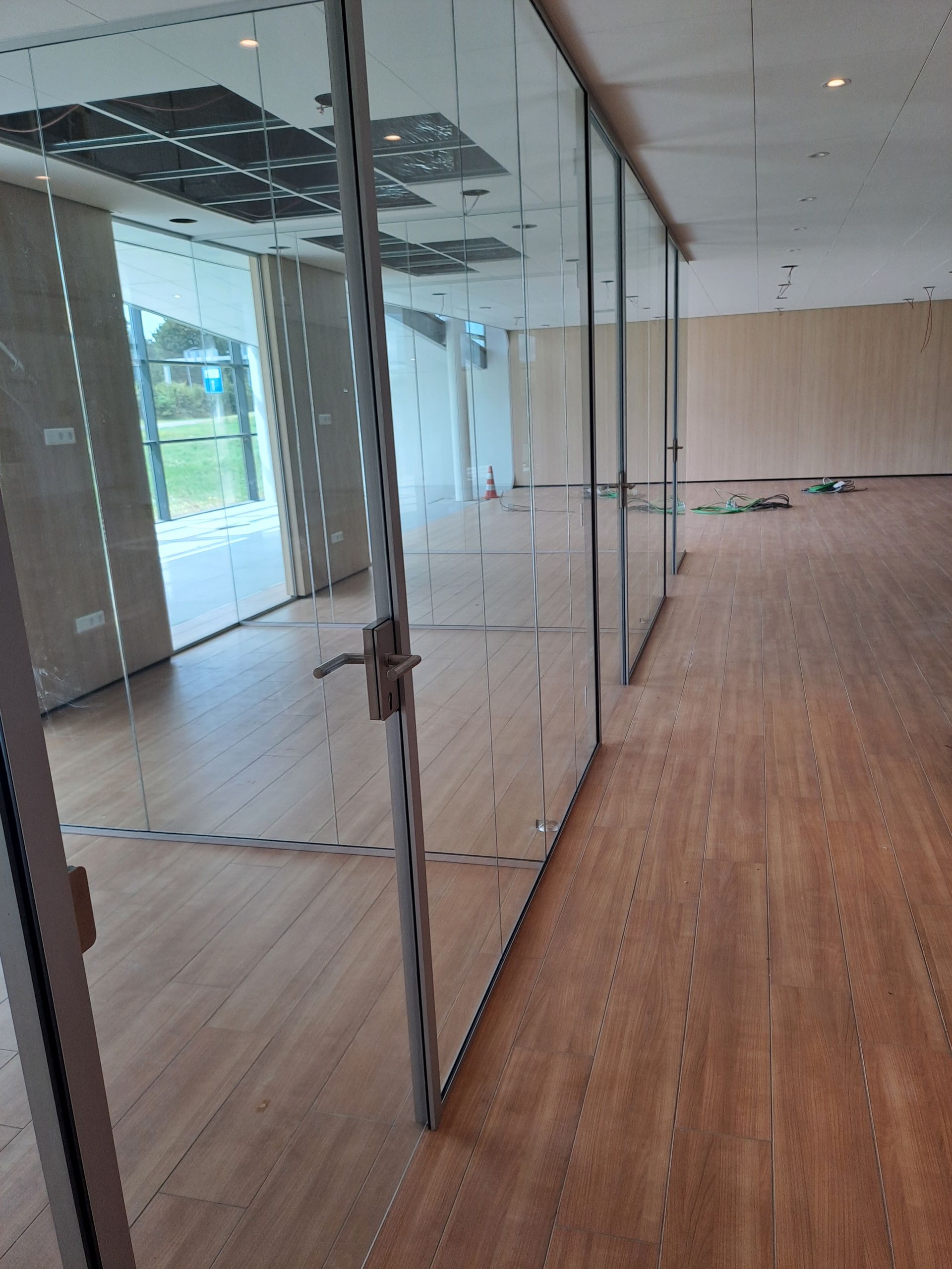 Een lege kamer met houten vloeren en glazen wanden