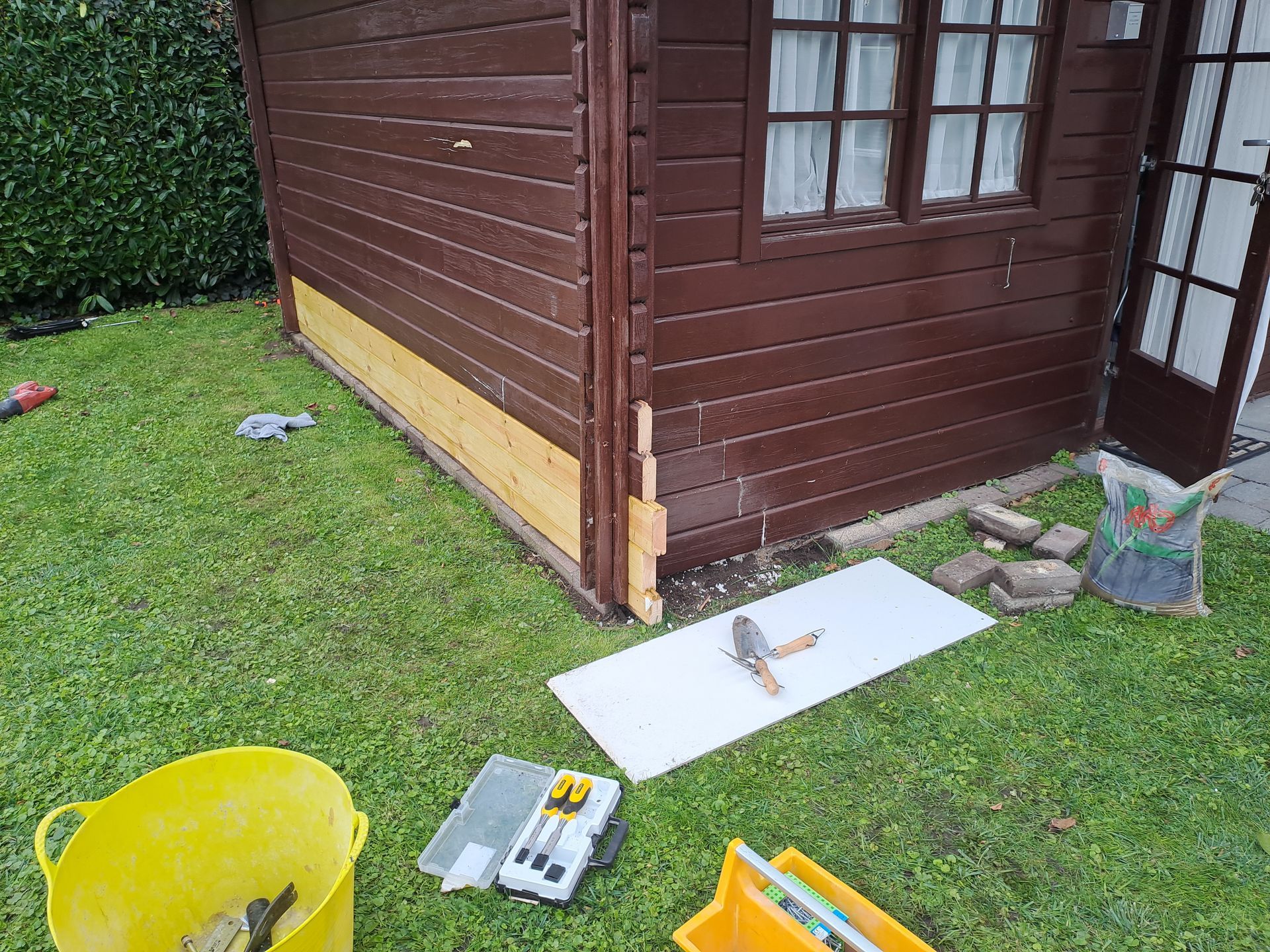 In een achtertuin wordt een houten schuur gerepareerd.