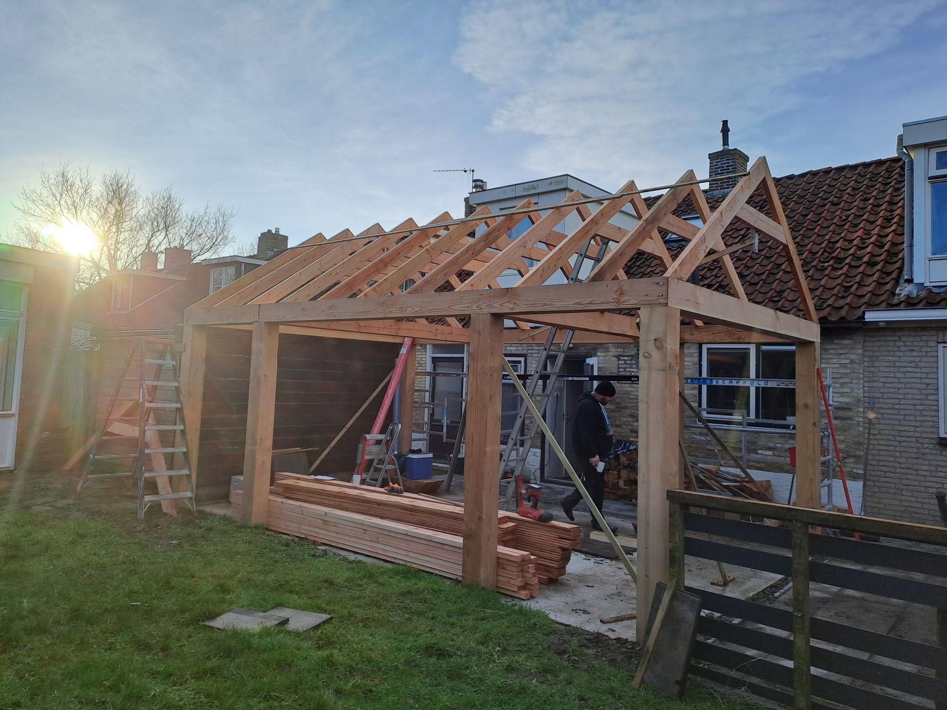 In de achtertuin van een huis wordt een houten constructie gebouwd.