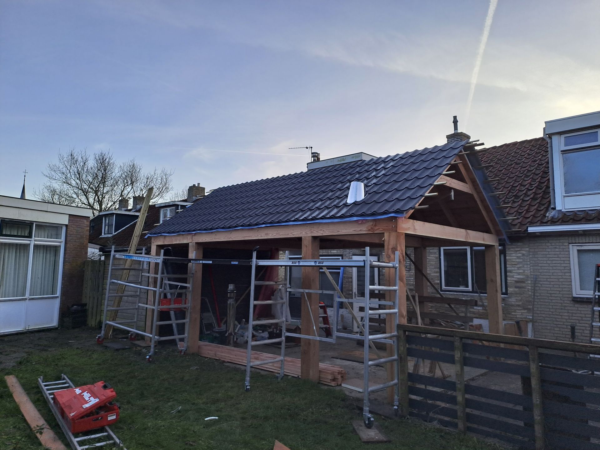 In de achtertuin van een huis wordt een houten constructie gebouwd.