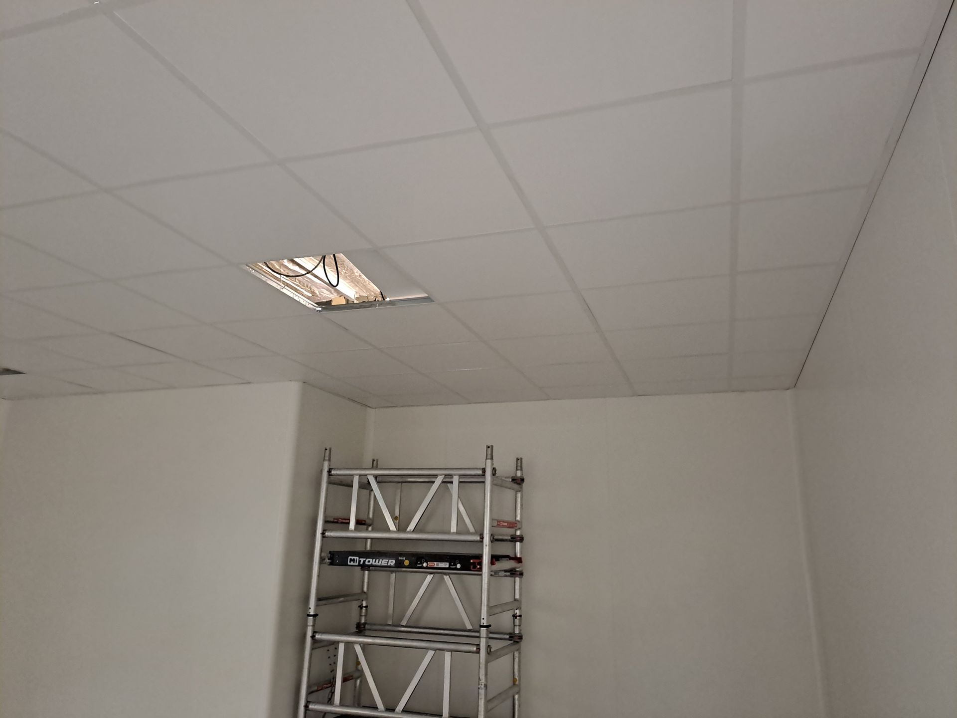 Een kamer met een ladder en een plafond met licht erop