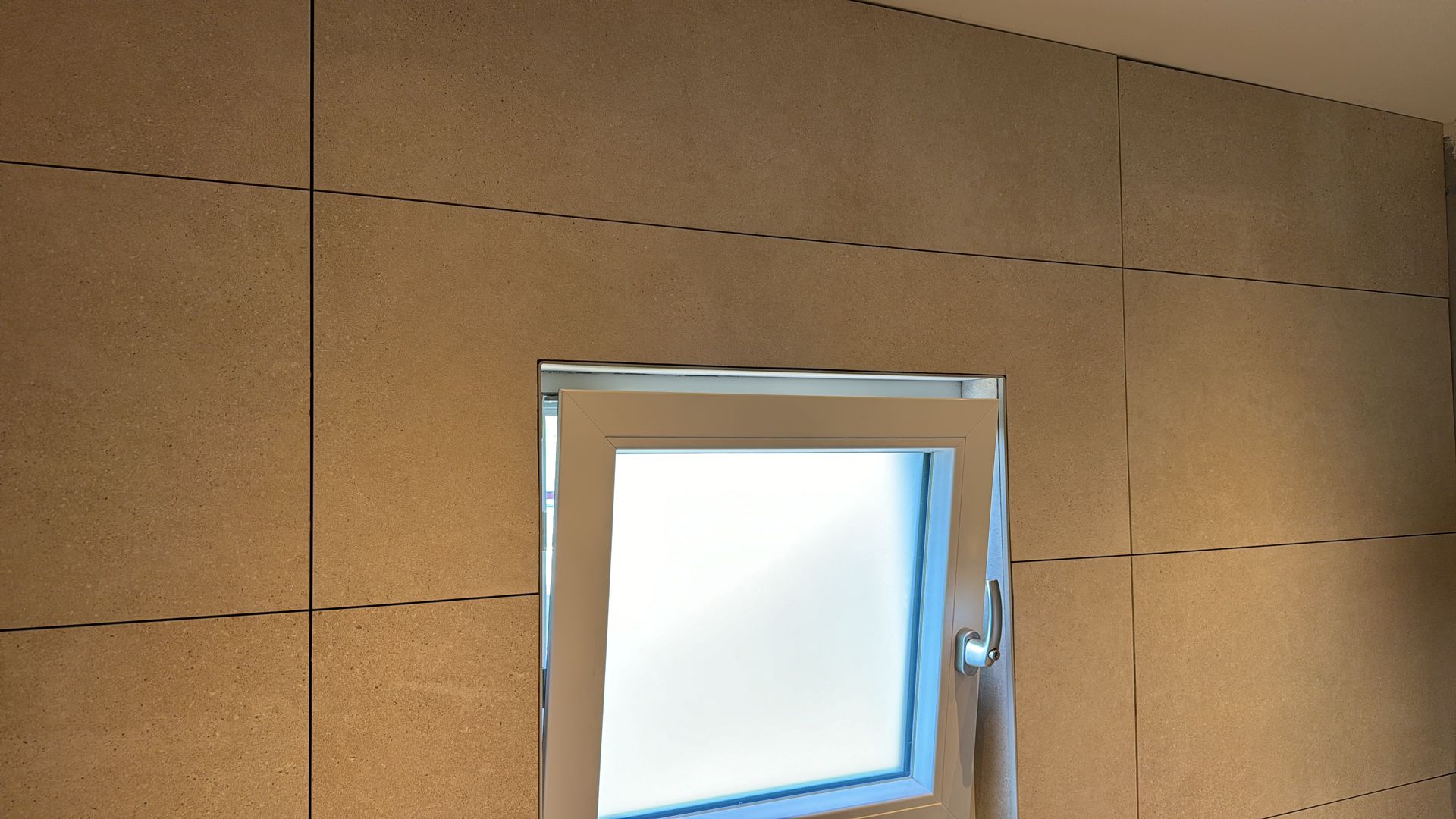 Een raam in een kamer met een houten muur