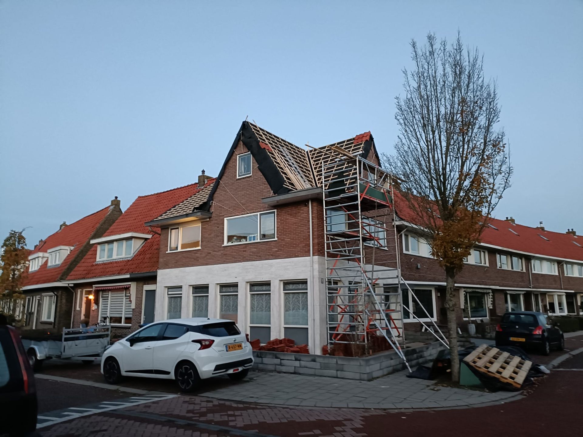 Een bakstenen huis met een witte auto ervoor geparkeerd.