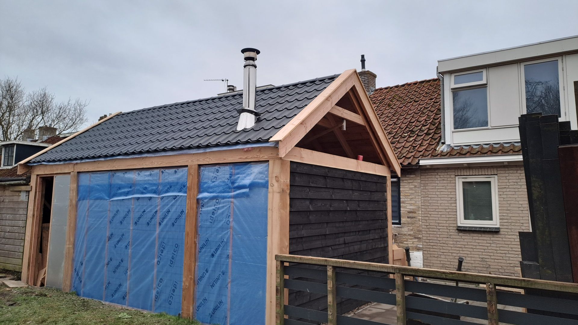 Een houten gebouw met een blauw zeil aan de zijkant