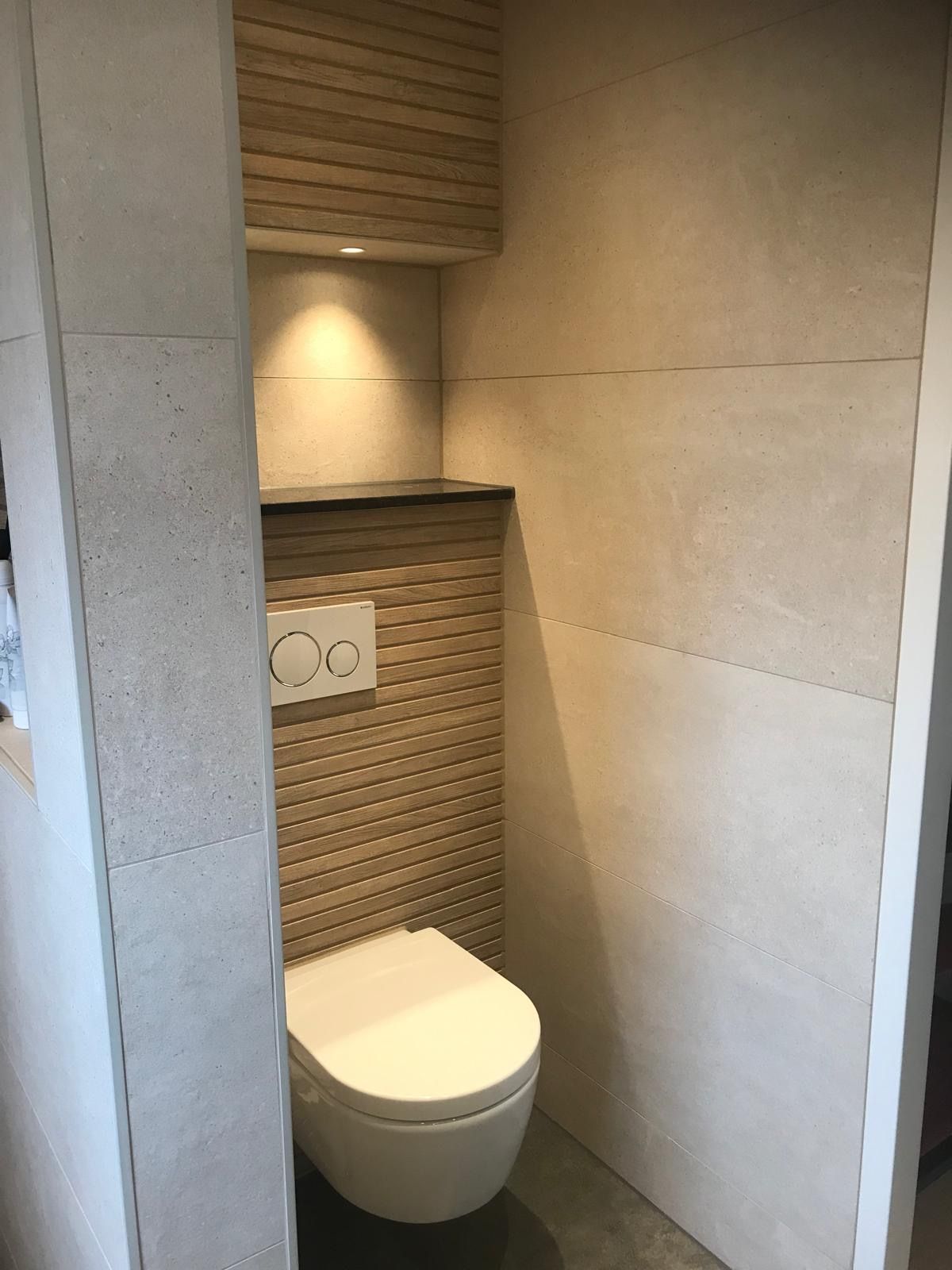 Een badkamer met toilet en een plank aan de muur