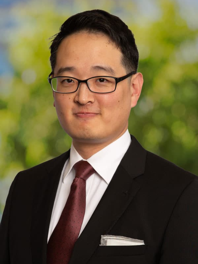 Man in suit, smiling, outdoors.