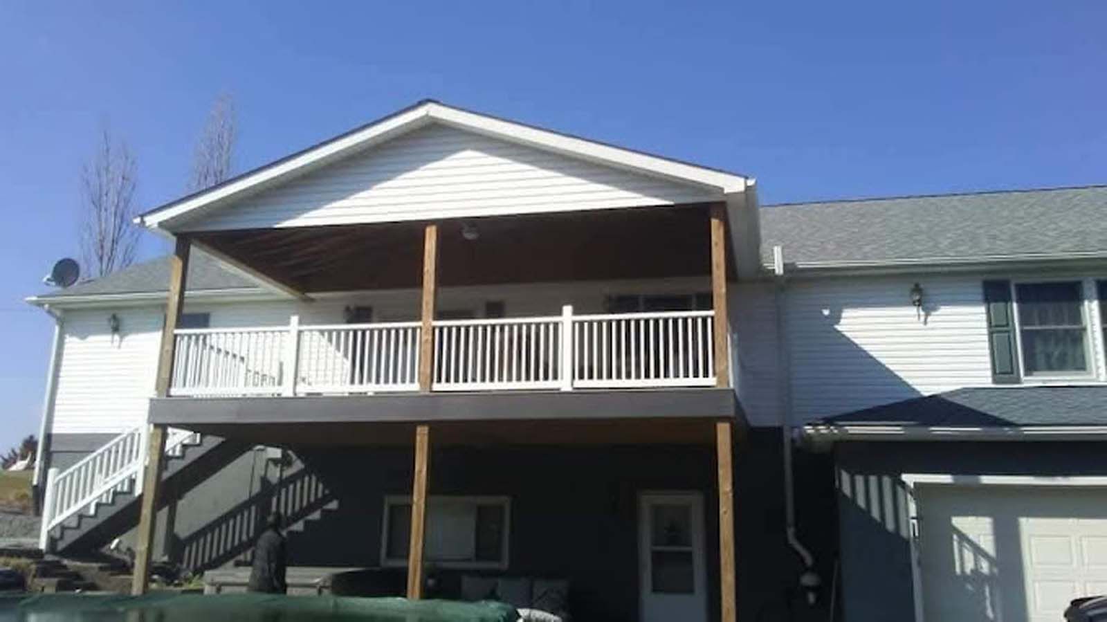 A large white house with a large deck and stairs.