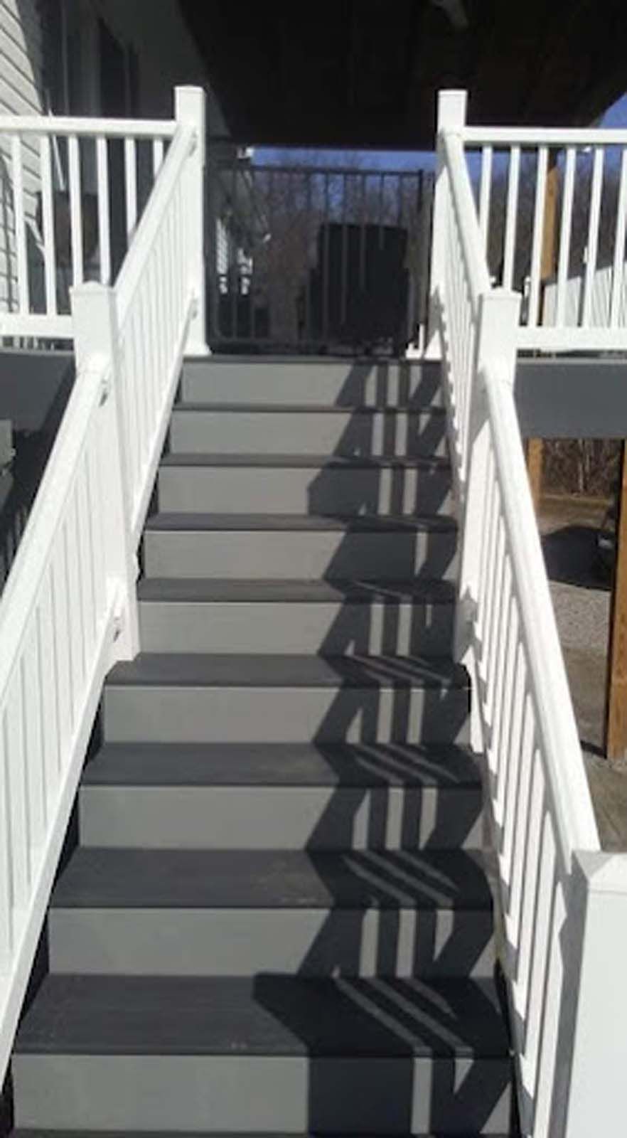 A set of stairs leading up to a deck with a white railing.