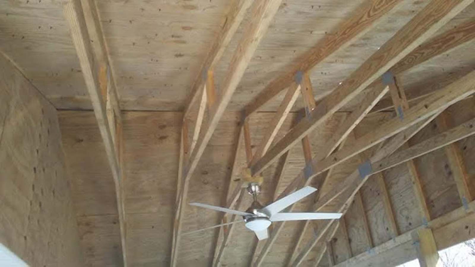 A ceiling fan is hanging from the ceiling of a wooden structure.
