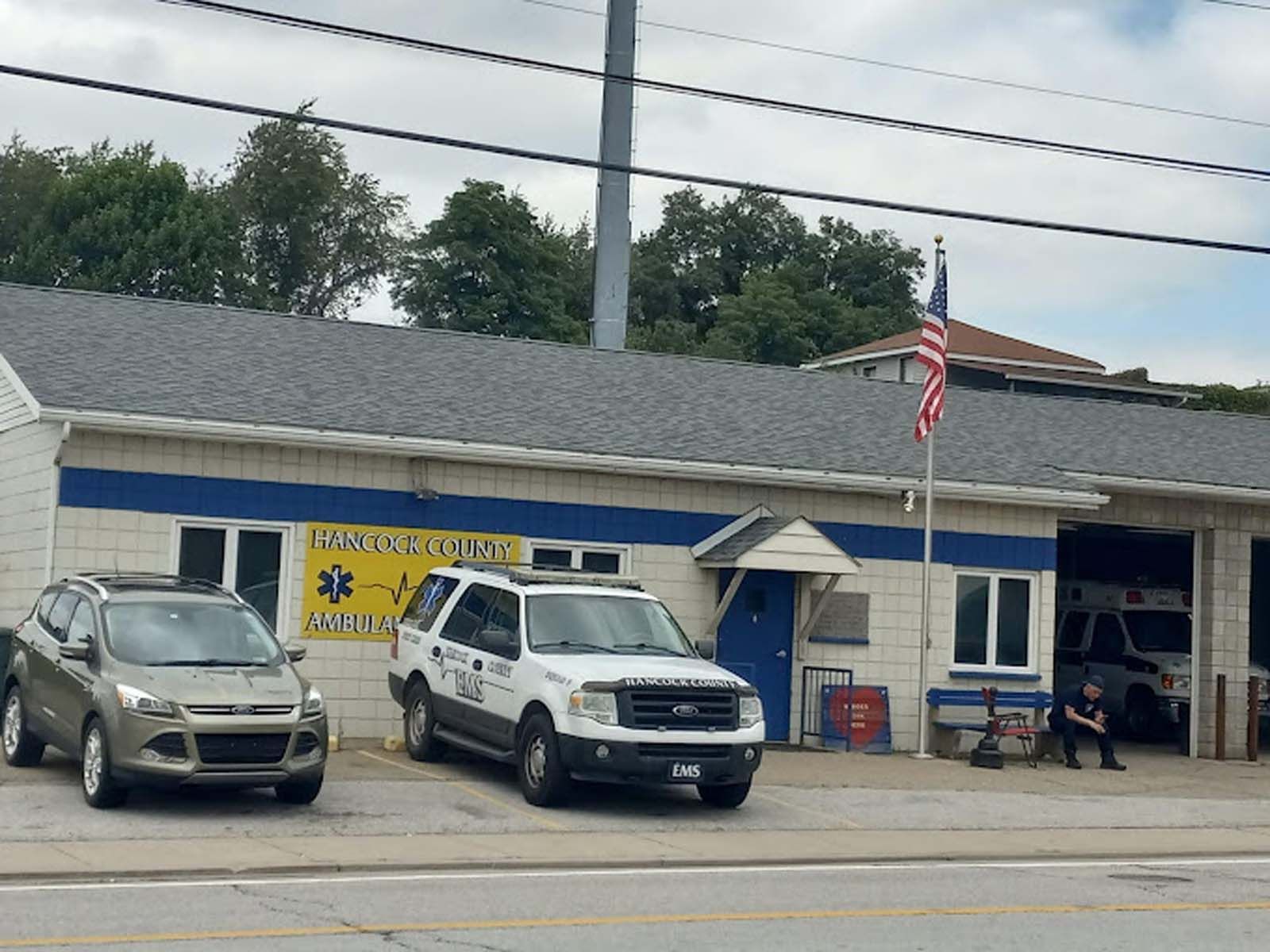 Three cars are parked in front of a fire station