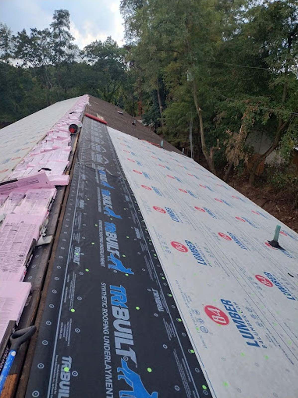 The roof of a house is being covered with a roofing material.