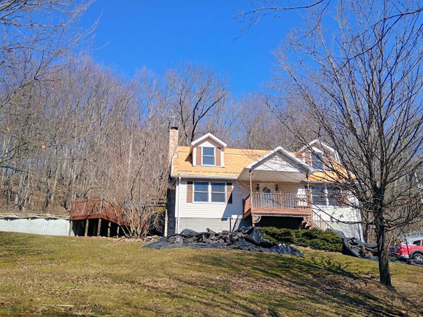 A white house with a wooden roof is sitting on top of a grassy hill.