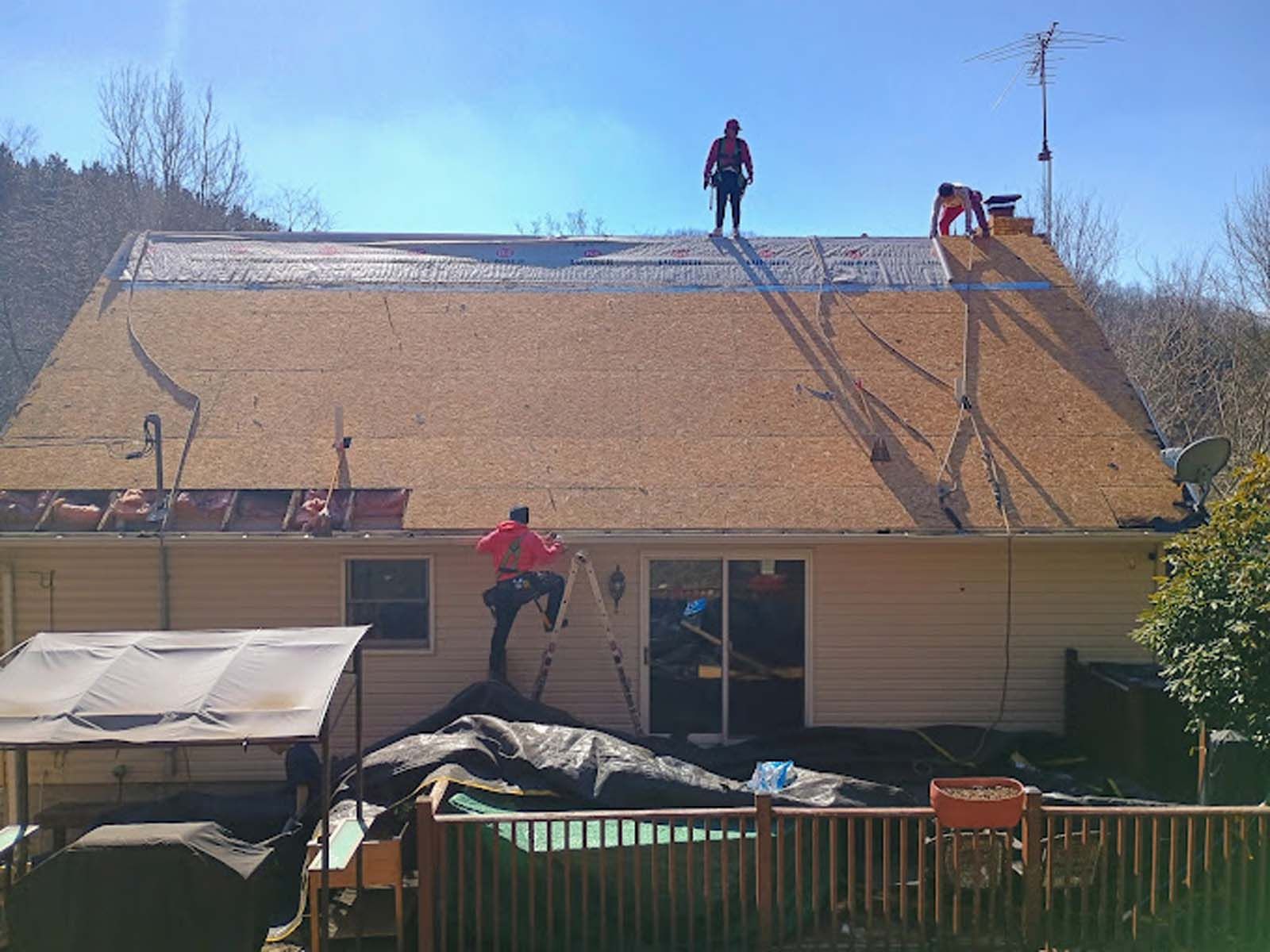 Two men are working on the roof of a house