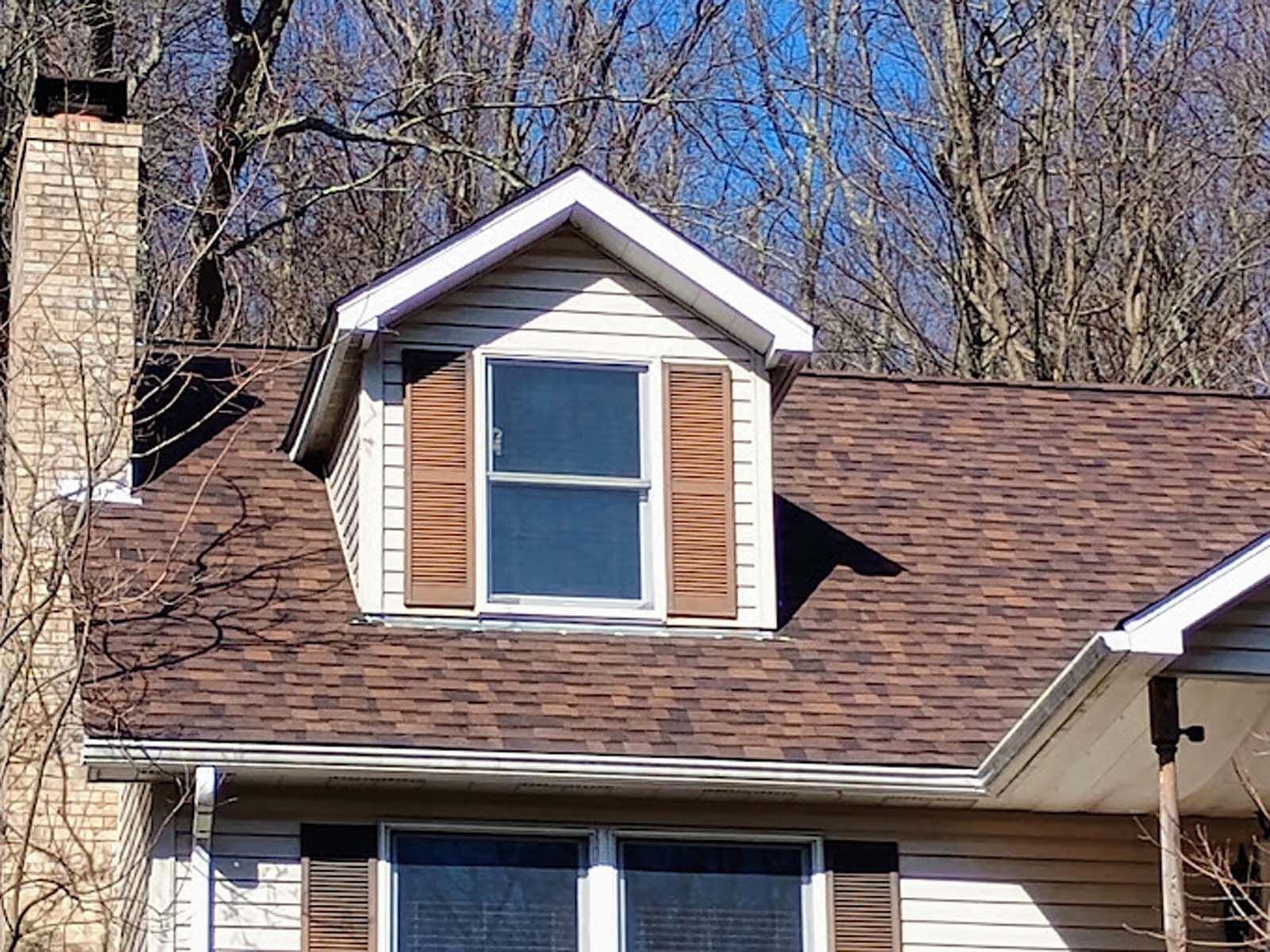 A house with a window on the roof and a chimney.