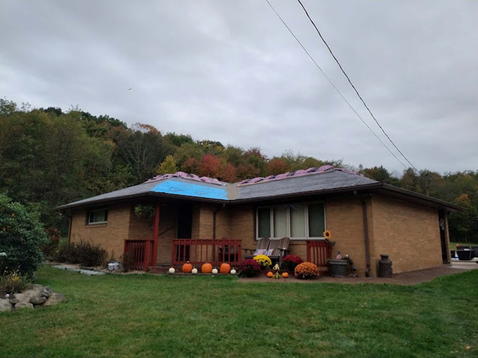 A brick house with a blue tarp on the roof.