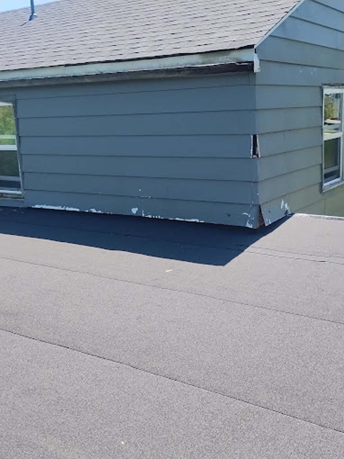 A gray house with a black roof and a gray siding.