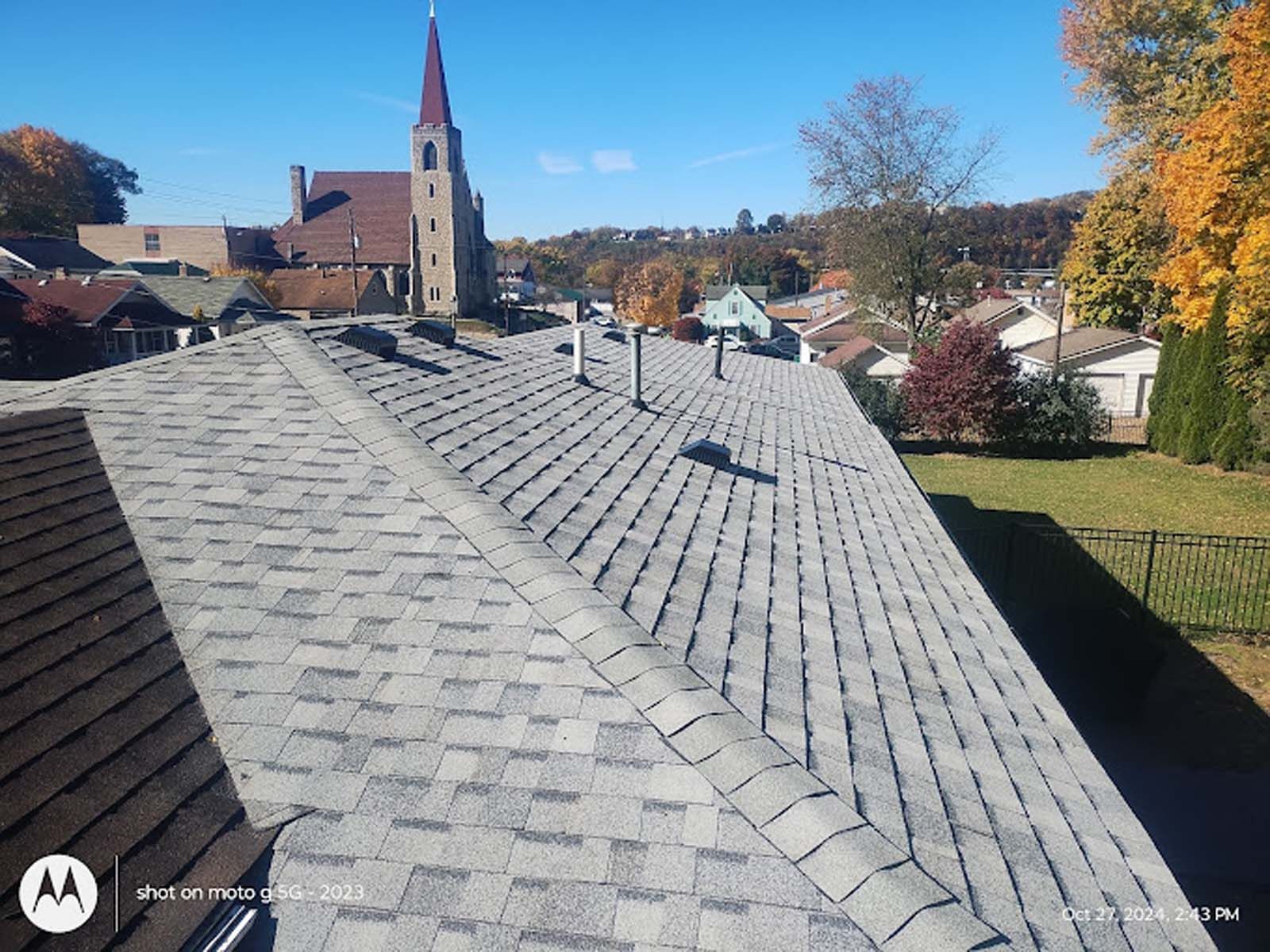 The roof of a house with a church in the background.