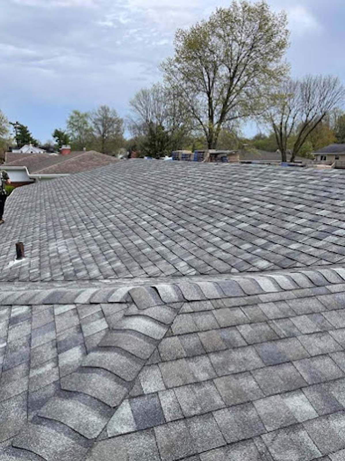 A roof with a lot of shingles on it and trees in the background.
